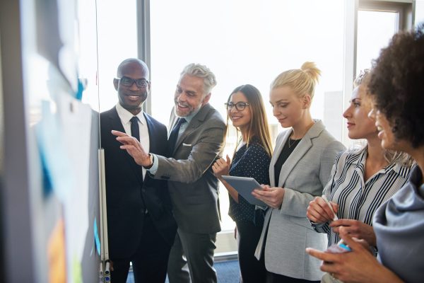 Smiling colleagues strategizing together on a whiteboard in an office